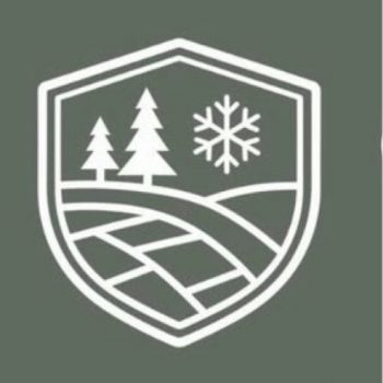 A white shield emblem on a green background featuring two pine trees, a snowflake, and stylized fields or rolling hills.