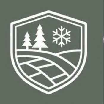 A white shield emblem on a green background featuring two pine trees, a snowflake, and curved lines representing a landscape or road.
